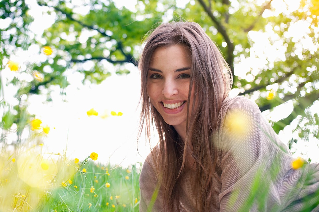 Adult woman smiling as she lays on the grass with the sun shining